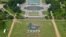 People on the National Mall in Washington, looking toward the World War II Memorial, Aug. 25, 2016, recreate a giant, living version of the National Park Service emblem, using brown, green and white umbrellas. 