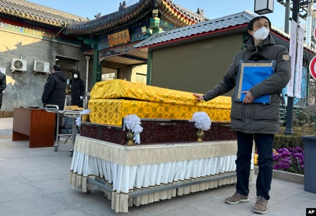 FILE - Family members in protective gear collect the cremated remains of their loved one bundled with yellow cloth at a crematorium in Beijing on Dec. 17, 2022. (AP Photo/Ng Han Guan, File)