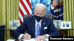 El presidente Joe Biden firma las primera órdenes ejecutivas de su mandato dentro de la Oficina Oval de la Casa Blanca en Washington D.C., el 20 de enero de 2021. 