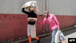 FILE - A woman walks with her blind husband as they carry food collected during a food distribution leaded by the international NGO Gift to the Givers, in Johannesburg, South Africa, Oct. 14, 2020.