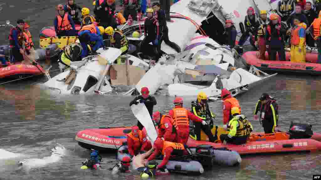 Rescue personnel in a rubber dinghy lift a passenger (bottom C) from the waters around the wreckage of a TransAsia ATR 72-600 turboprop plane that crash-landed into the Keelung river outside Taiwan&#39;s capital Taipei in New Taipei City.