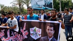 FILE - Hundreds of supporters of exiled former Gaza strongman Mohammed Dahlan carry a banner with his picture during a protest against metal detectors Israel erected at the Al-Aqsa Mosque compound in Jerusalem, in Gaza City, July 20, 2017. 