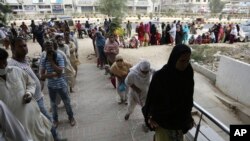 People wait to receive cash under the government's Ehsaas Emergency Cash Program for families in need during a government-imposed nationwide lockdown to help contain the spread of the coronavirus, in Karachi, Pakistan, April 14, 2020.