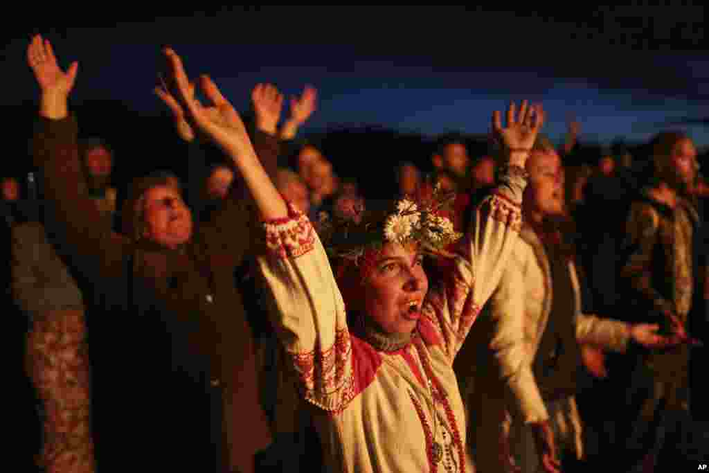 People wearing traditional Russian village-styled clothes, celebrate the summer solstice around a bonfire in Okunevo village, some 200 kilometers (124 miles) northeast from Siberian city of Omsk, June 21, 2021.