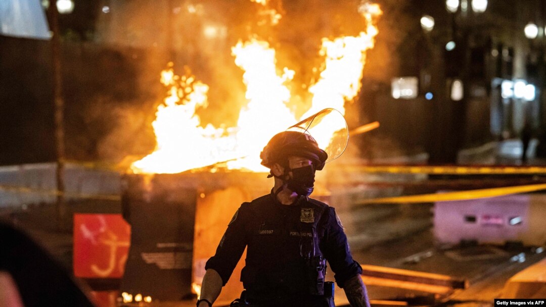 Police respond to a fire set by protesters following the police shooting of a man on April 17, 2021, in Portland, Oregon.