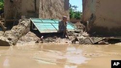 A man sits near his damaged house after heavy flooding in Baghlan province, Afghanistan, on May 12, 2024.