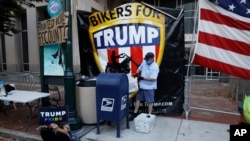 A postal worker collects mail from a mailbox inside the protest pen, as a handful of supporters of President Donald Trump continue to demonstrate, outside the Pennsylvania Convention Center in Philadelphia, Nov. 10, 2020. 