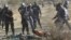 South African policemen give instructions to an injured miner after striking miners were shot outside a South African mine in Rustenburg, 100 km northwest of Johannesburg on August 16, 2012. 