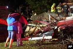 Los transeúntes se abrazan mientras los socorristas trabajan para liberar a una víctima después de que un árbol cayera sobre una casa en Natchez, Mississippi, el sábado 28 de diciembre de 2024. (Thomas Graning/The Natchez Democrat vía AP)