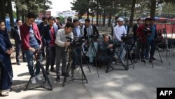 FILE - Afghan journalists gather during a news report at the Shahr-e-Naw Park in Kabul, April 30, 2019.