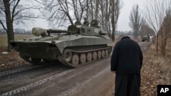 Un sacerdote saluda mientras un tanque separatista aparentemente regresa a su base, cerca de Donetsk.