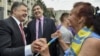 Ukrainian President Petro Poroshenko, left, and then-governor of Odessa region Mikheil Saakashvili, center, are greeted by a local resident near the regional state administration in Odessa, Ukraine, May 30, 2015.