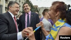 Ukrainian President Petro Poroshenko, left, and then-governor of Odessa region Mikheil Saakashvili, center, are greeted by a local resident near the regional state administration in Odessa, Ukraine, May 30, 2015.