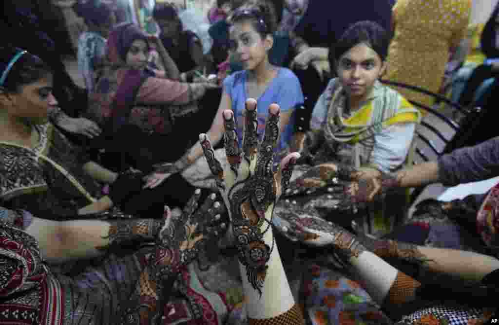 Perempuan muslim Pakistan menghiasi tangan mereka dengan henna untuk merayakan Idulfitri setelah sebulan menjalani ibadah puasa Ramadan, di Karachi, Pakistan, Selasa, 4 Juni 2019. (Foto: Fareed Khan/AP)