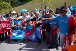 FILE - Supporters of People's Justice Party gather outside the National Palace to give support to Anwar Ibrahim in Kuala Lumpur, Malaysia, Wednesday, Feb. 26, 2020.