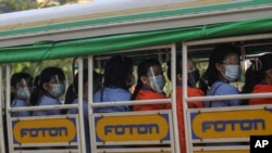 Factory workers wearing protective face masks and shields ride a truck as they go to their works in Hlaing Tharyar Industrial Zone Monday, Oct. 12, 2020, on the outskirts of Yangon, Myanmar. Myanmar government allowed Monday to resume Cut-Make-Pack …