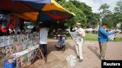 FILE - People read newspapers at a street side stand in central Phnom Penh.