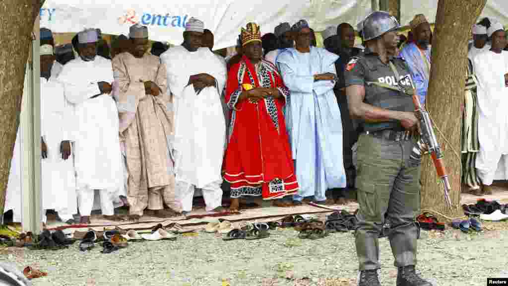 A police officer stands guard as Muslims pray at a prayer ground in Abuja.