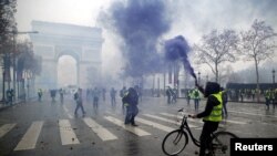 Protesters wearing yellow vests, a symbol of a FILE - French drivers' protest against higher diesel taxes, face off with French riot police during clashes at the Place de l'Etoile near the Arc de Triomphe in Paris, France, Dec. 1, 2018.