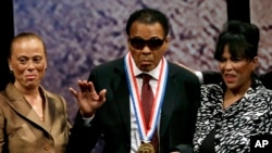 L’ex-champion de boxe, Mohamed Ali, au centre, salue de la main, aux côtés de sa femme Lonnie Ali, à gauche, et de sa belle-sœur Marilyn Williams, à droite, après avoir reçu la Médaille de la Liberté lors d'une cérémonie au national Constitution Center à Philadelphie, 13 septembre 2012. 