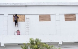 Trabajadores en Ciudad Belice protegen ventanas ante la llegada del huracán Nana el 2 de septiembre de 2020.