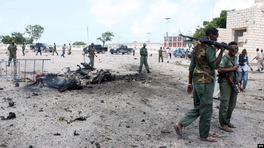 Petugas keamana Somalia berjalan melewati mobil yang hancur akibat ledakan bom di gedung parlemen di luar gedung parlemen Somalia di Mogadishu (5/7).
