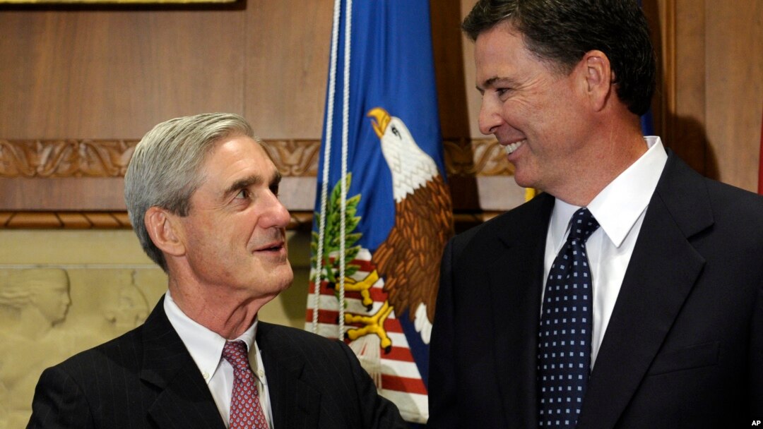 FILE - Former FBI Director James Comey talks with his predecessor, Robert Mueller, before Comey was officially sworn into office in Washington, Sept. 4, 2013.