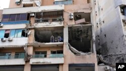 FILE - Investigators stand on an apartment building where an apparent Israeli strike Tuesday killed top Hamas political leader Saleh Arouri, in the southern suburb of Beirut that is a Hezbollah stronghold, Lebanon, Wednesday, January 3, 2024. 