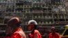 Petugas ambulans berjalan melewati sebuah gedung bernama New Lucky House di Hong Kong yang terbakar pada Rabu, 10 April 2024. (Foto: AP)