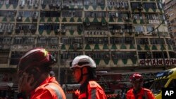Ambulance workers walk past a building called New Lucky House where a fire started in Hong Kong, April 10, 2024. 