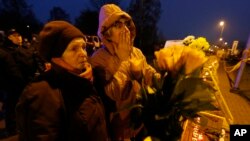 Warga Latvia meletakkan karangan bunga dan lilim di depan supermarket Maxima di Riga, Latvia (22/11).