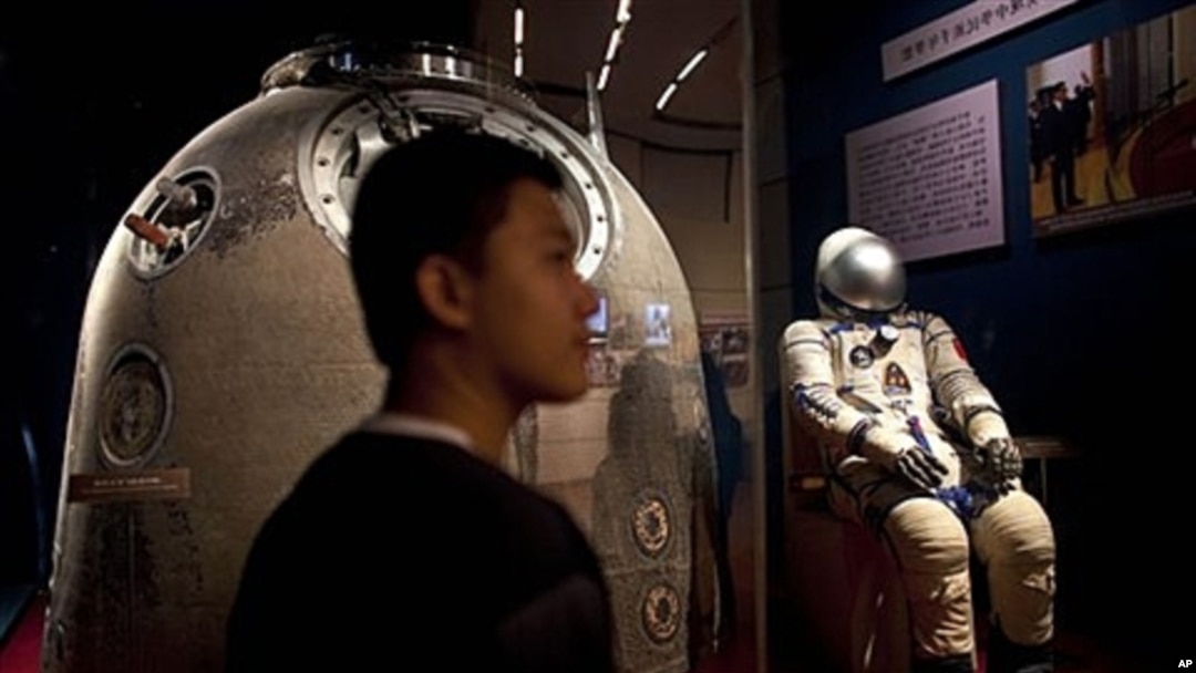 Visitor stands near the Shenzhou 5 re-entry capsule at an exhibition in Beijing, July 6, 2011.