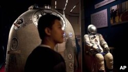 Visitor stands near the Shenzhou 5 re-entry capsule at an exhibition in Beijing, July 6, 2011.