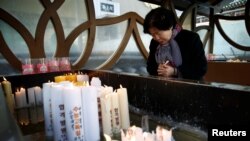 A woman prays for her grandchild taking the annual college entrance examinations at a Buddhist temple in Seoul, South Korea, Nov. 17, 2016.