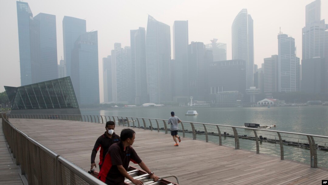 Seorang pekerja memakai masker di tengah kabut asap yang menyelimuti Singapura (10/9). (AP/Ng Han Guan)