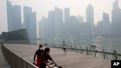 Seorang pekerja memakai masker di tengah kabut asap yang menyelimuti Singapura (10/9). (AP/Ng Han Guan)