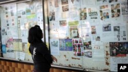 This picture taken on January 19, 2011 shows a young woman reading advertisements for "maids wanted" outside a shopping mall in Kuala Lumpur. 