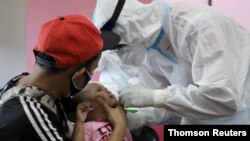 2일 말레이시아 사이버자야에서 의료진이 어린이의 신종 코로나바이러스 검사용 검체를 채취하고 있다.
