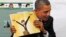 President AS Barack Obama memegang sebuah buku berisi gambar kartun dirinya, di sebuah kelas pertumbuhan anak-anak di Eastfield College di Mesquite, Texas. (Foto: Dok)