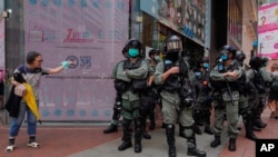 Riot police standing guard as a woman tries to cross the street in the Causeway Bay district of Hong Kong, May 27, 2020. 