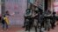 Riot police standing guard as a woman tries to cross the street in the Causeway Bay district of Hong Kong, May 27, 2020. 