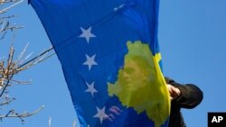 Seorang pekerja menggantung bendera Kosovo dalam rangka peringatan 12 tahun kemerdekaan negara itu di Ibu Kota Pristina, Senin, 17 Februari 2020. (Foto: AP)