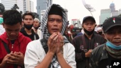 Muslim men pray during a protest against the new Job Creation Law approved by Parliament last week in Jakarta, Indonesia, Oct. 13, 2020. 