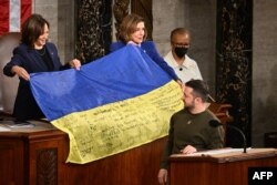 Президент України Володимир Зеленський дарує український прапор тодішній спікерці Палати представників США Ненсі Пелосі, а такожі віце-президентці США Камалі Гарріс під час виступу в Конгресі США, 21 грудня. 2022 р. (Jim WATSON/AFP)