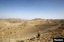 FILE - A soldier stands guard along the border fence outside the Kitton outpost on the border with Afghanistan in North Waziristan, Pakistan, Oct. 18, 2017.