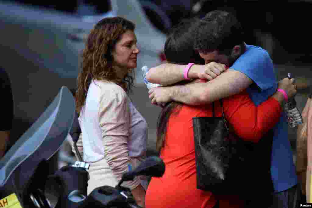 Los familiares de los desaparecidos reportados se abrazan en la entrada de un hotel despu&#233;s de visitar el sitio del edificio residencial parcialmente derrumbado.