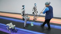 Seorang staf membersihkan lantai di sebelah robot-robot humanoid selama forum &quot;Digital Almaty 2025&quot;, di Almaty, Kazakhstan.