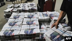 FILE - An employee loads freshly printed packages of Le Monde daily newspaper with a picture of French president on the frontpage at the CIRA newspapers printing site in Saint-Vulbas eastern France, on April 20, 2023.