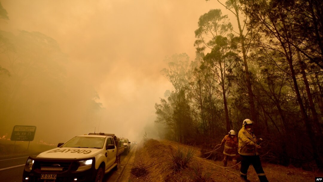 Firefighters tackle a bushfire in thick smoke in the town of Moruya, south of Batemans Bay, in New South Wales, Jan. 4, 2020. Up to 3,000 military reservists were called up to tackle Australia's bushfires as tens of thousands of people fled.