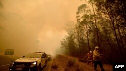 Firefighters tackle a bushfire in thick smoke in the town of Moruya, south of Batemans Bay, in New South Wales, Jan. 4, 2020. Up to 3,000 military reservists were called up to tackle Australia's bushfires as tens of thousands of people fled.